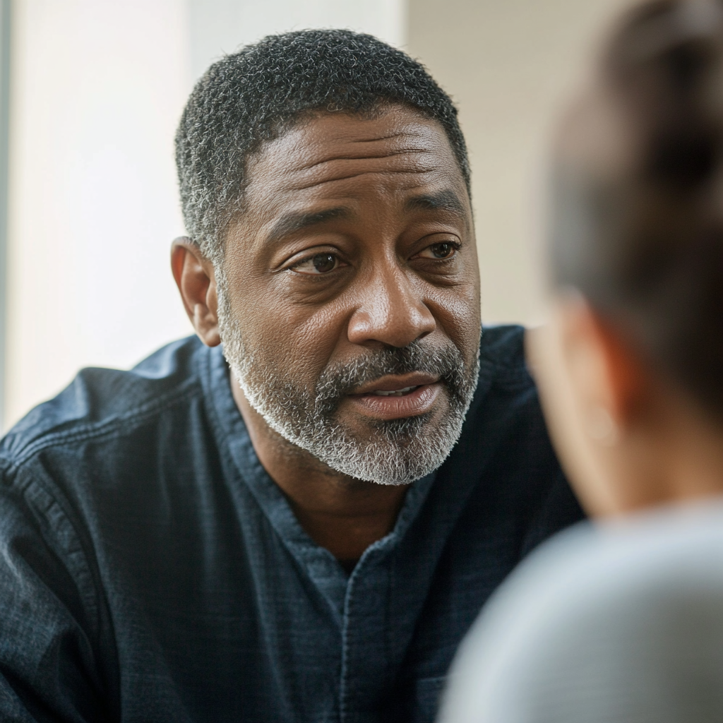 A black man talking seated in natural light.