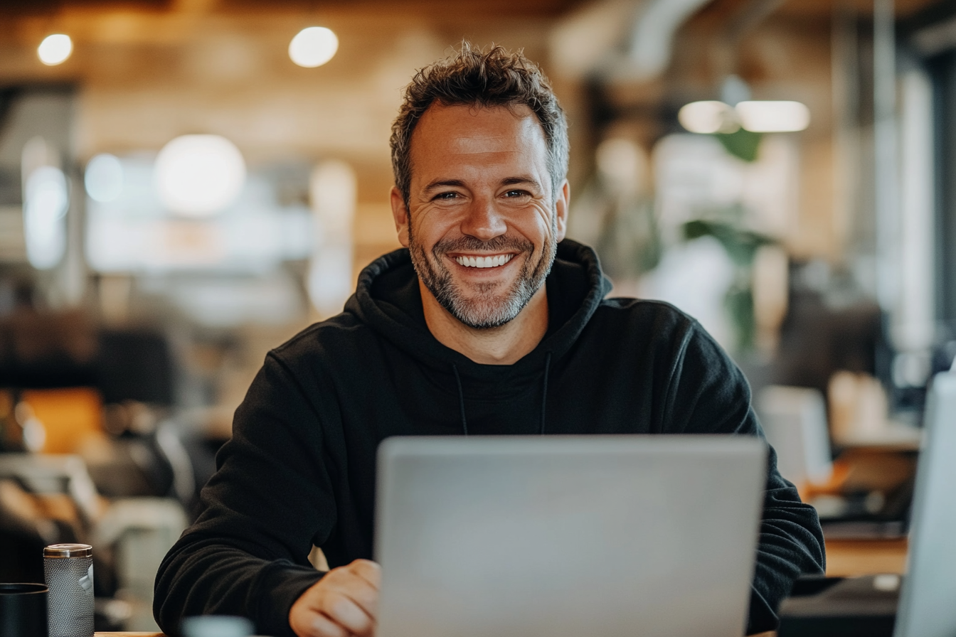 Businessman smiling at laptop, creating online advertising content.