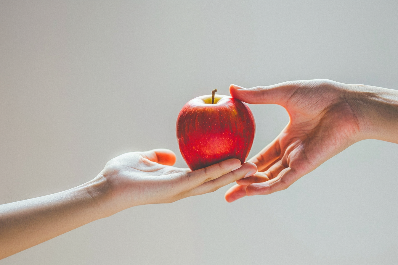 Hand offering apple symbolizes health education, promotion.