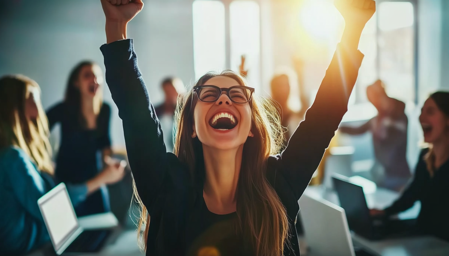 Laughing office workers surround woman with laptop in modern office