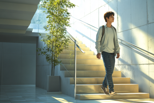 A Japanese man in smart outfit walking upstairs