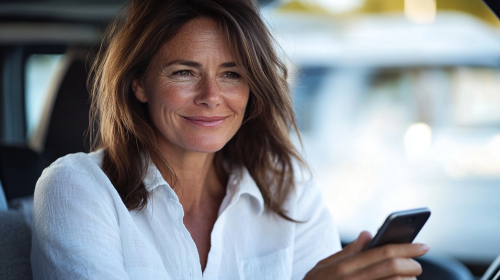 A Smiling Woman in Car Looking at iPhone