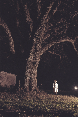 A Woman in White Witch with Flashlight at Night