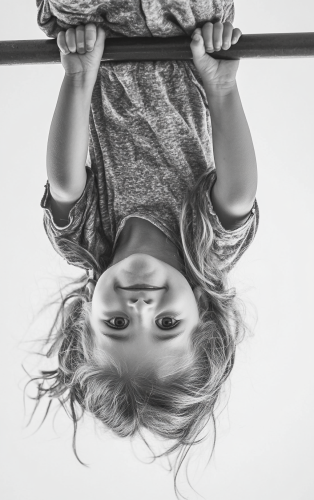 A happy girl on monkey bar, upside down