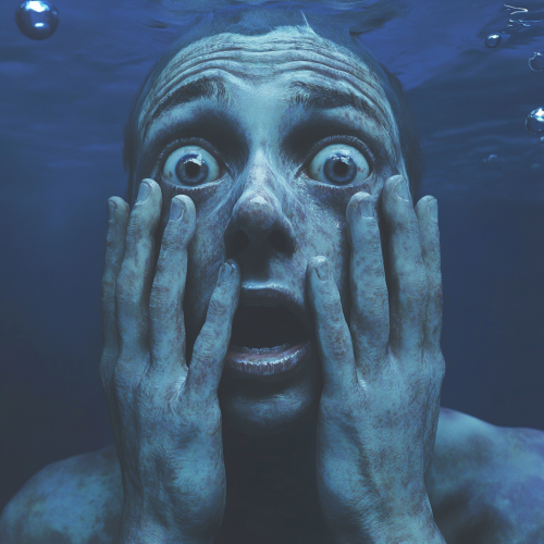 A person floating underwater, eyes wide open in fear