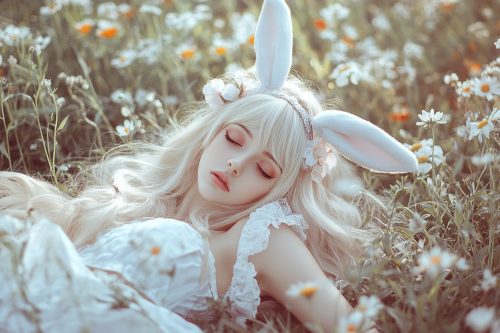 A young blonde woman in white dress in flowers.