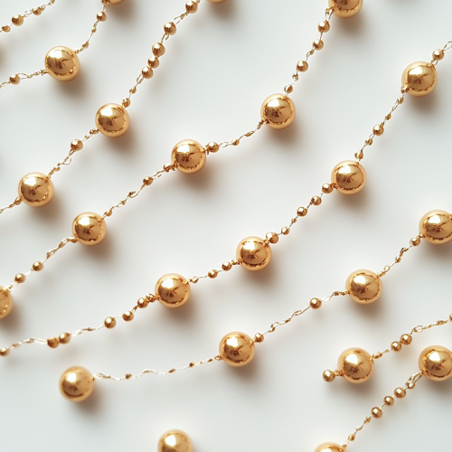 Golden garland of small round beads on white background.