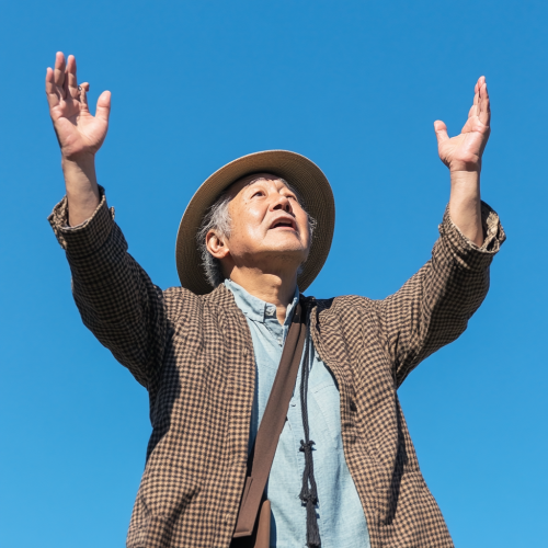 Japanese man in brown hat holding bag under sky