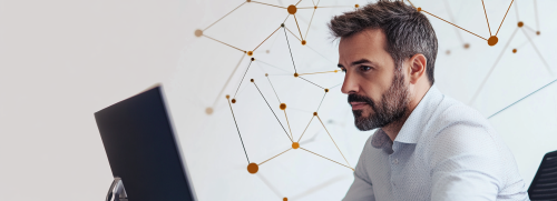 Man trades on computer with navy geometric shapes background.