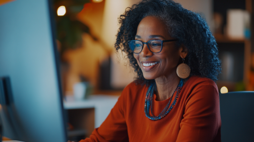 Middle-aged woman smiling in virtual meeting with red/blue clothing.