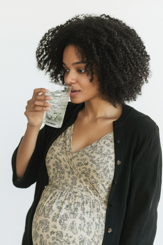 Pregnant woman doing drink photoshoot poses on camera