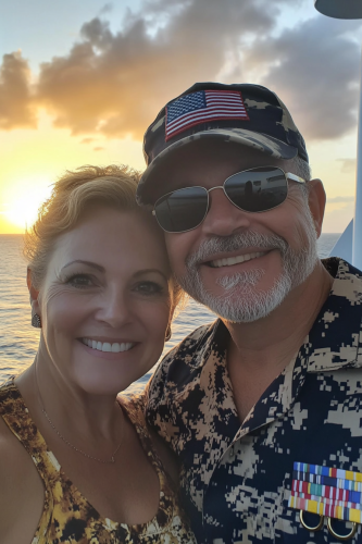 Smiling couple on cruise ship at sunset.