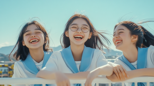 Three Japanese high school girls laughing on rooftop. Three Japanese high school girls laughing on rooftop.