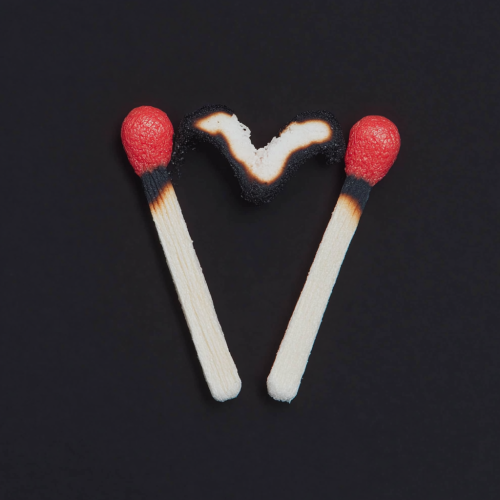 Two matchsticks forming heart shape, with burned effect.