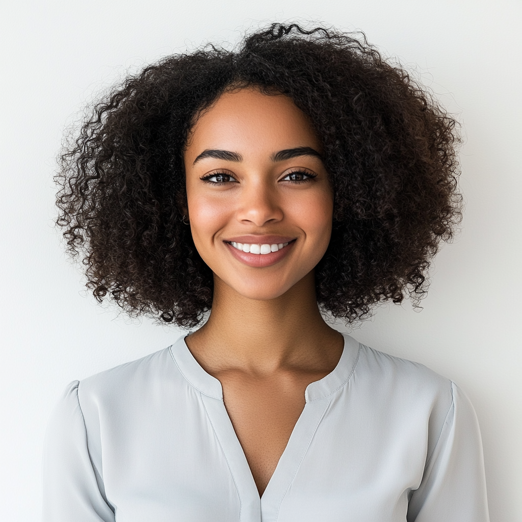 Friendly Black woman in 20s with curly hair smiling.