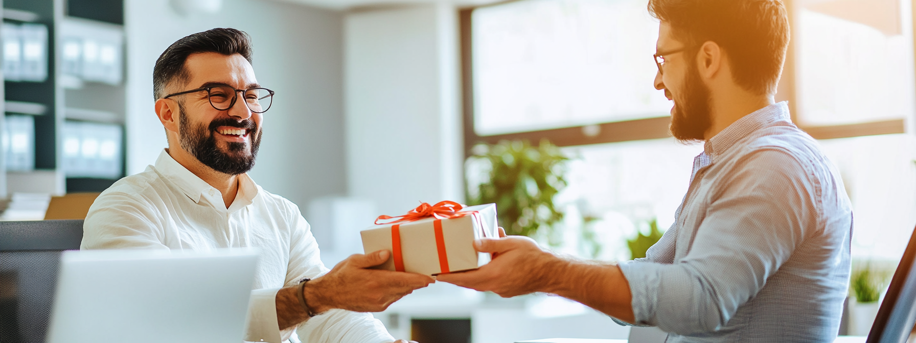 Male boss receives gift from male employee, both smiling