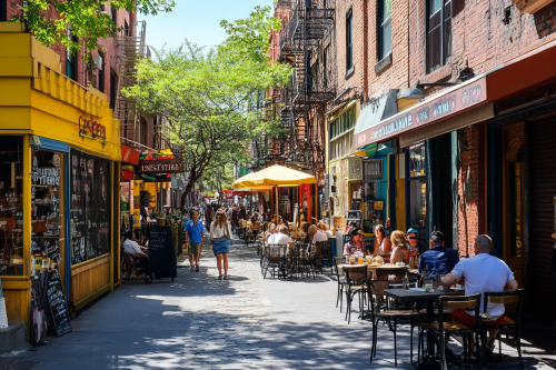 Busy street with shops, cafes, people dining outdoors