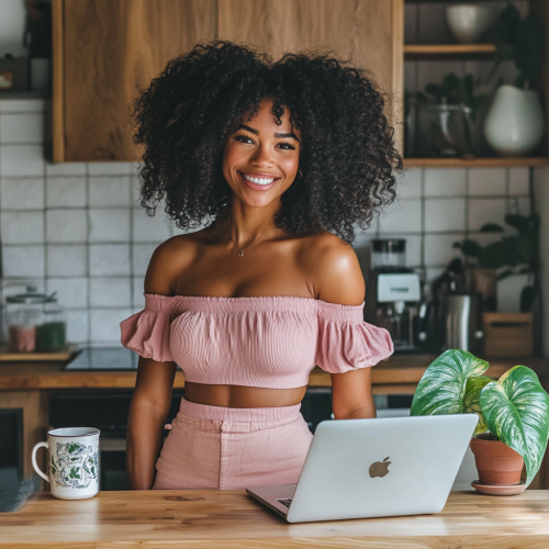Happy black woman with laptop in home kitchen.