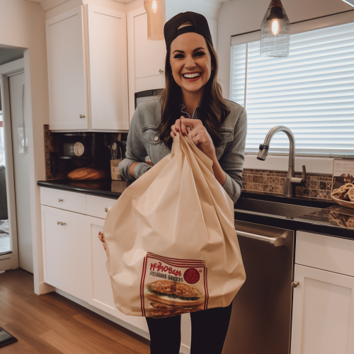 Happy woman holding a giant takeout bag at Superbowl party
