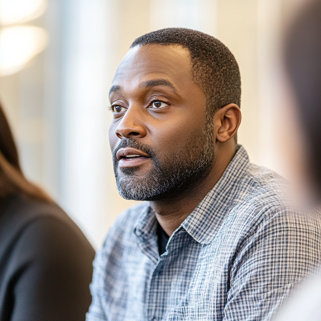 A black man talking seated in natural light.