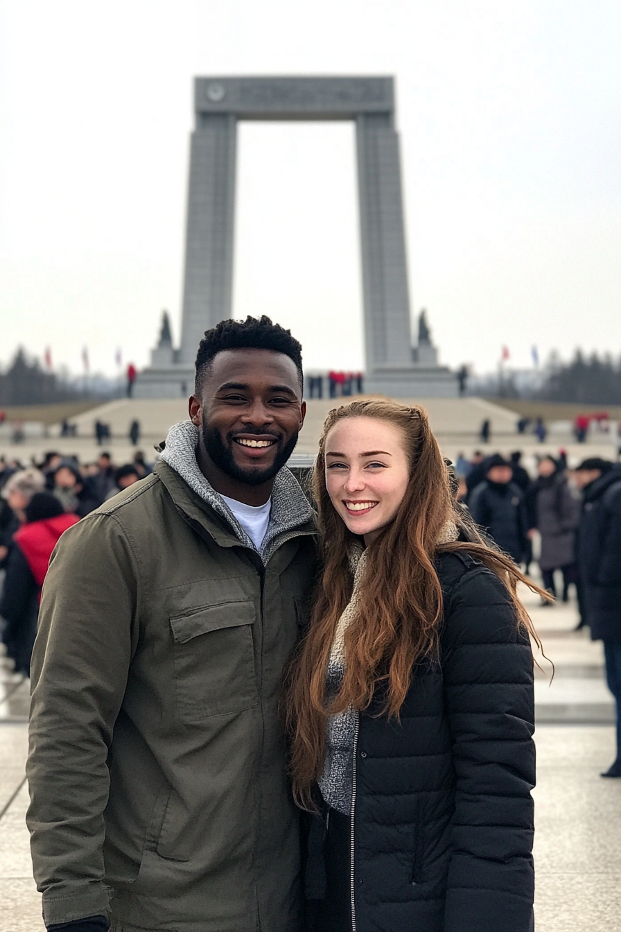 American couple at Reunification Arch with North Koreans in background.