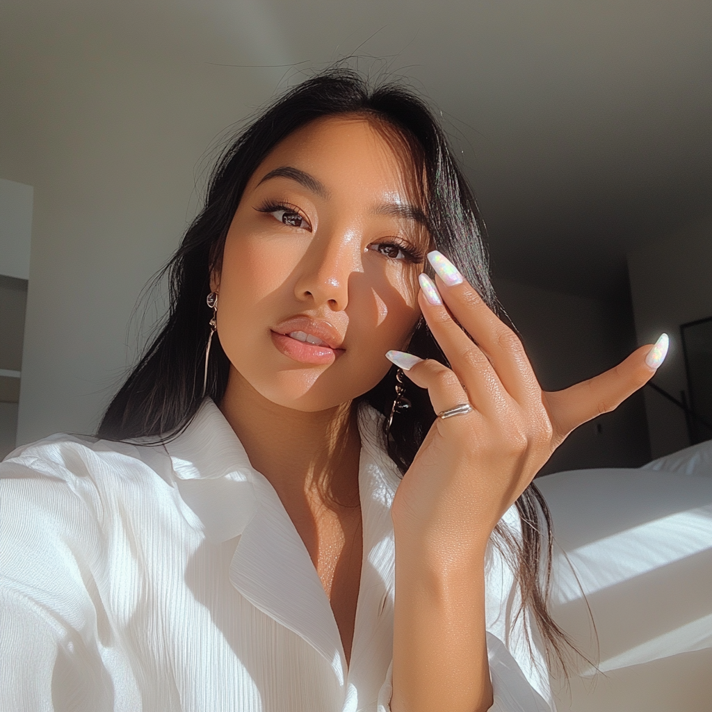 Asian woman showing glossy white iridescent nails, casual style.