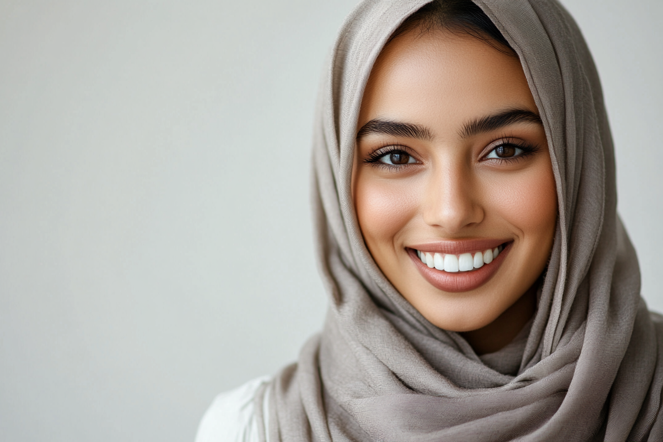 Beautiful hijabi woman in grey scarf, smiling at camera.