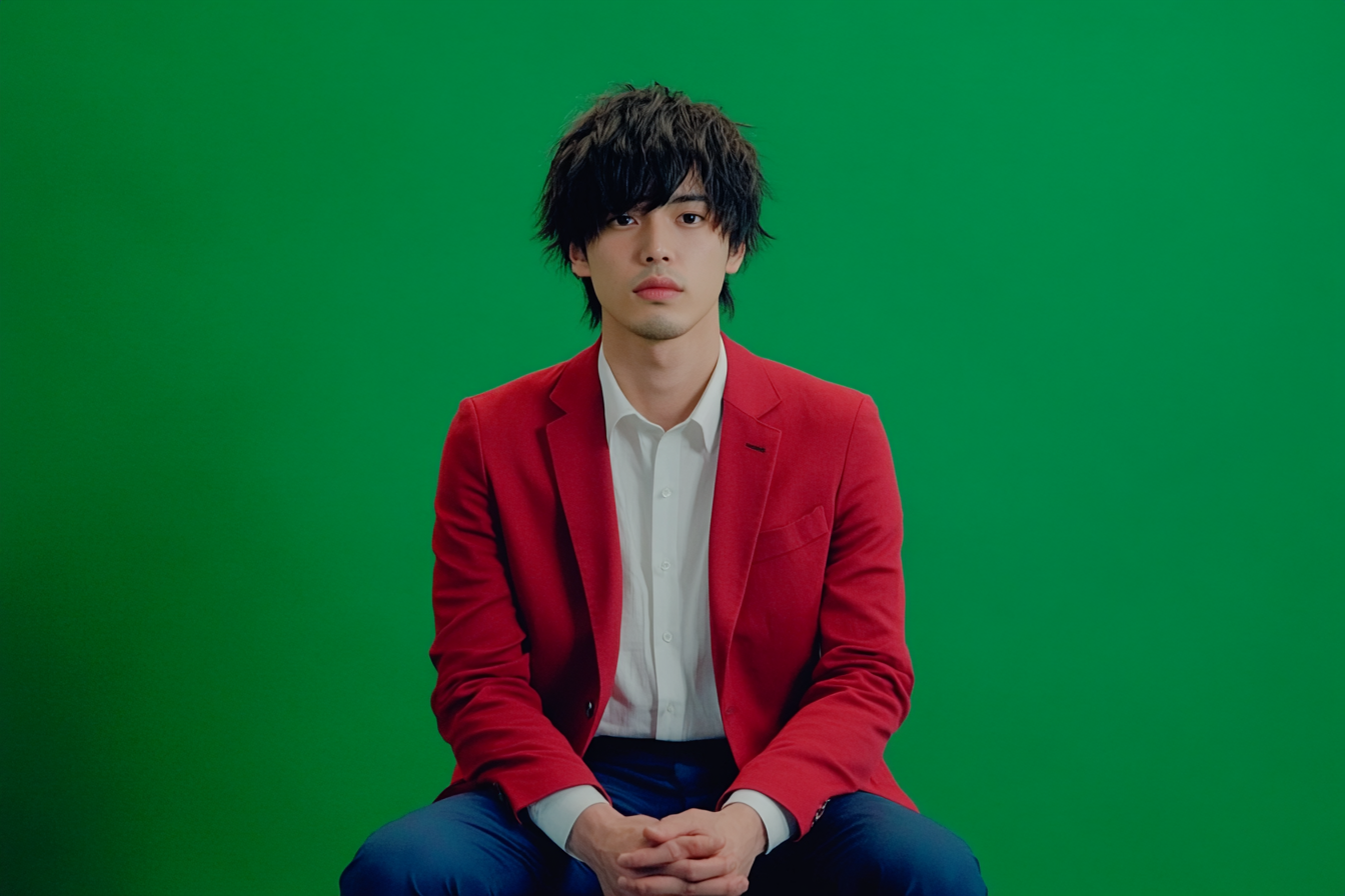 Japanese man in navy trousers & red blazer, smiling.