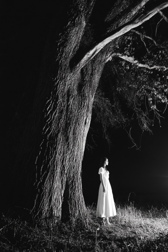 A Woman in White Witch with Flashlight at Night