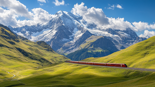 A long train travels through mountain with snowy peaks.