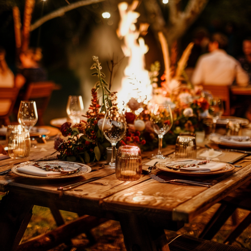 Beautifully set dining table near bonfire with flowers
