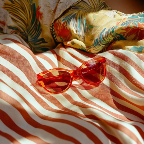 Person in Hawaiian shirt on beach blanket with sunglasses