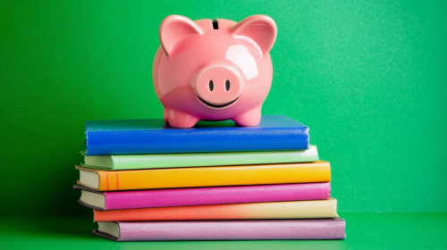 Pink piggy bank on books for education importance.