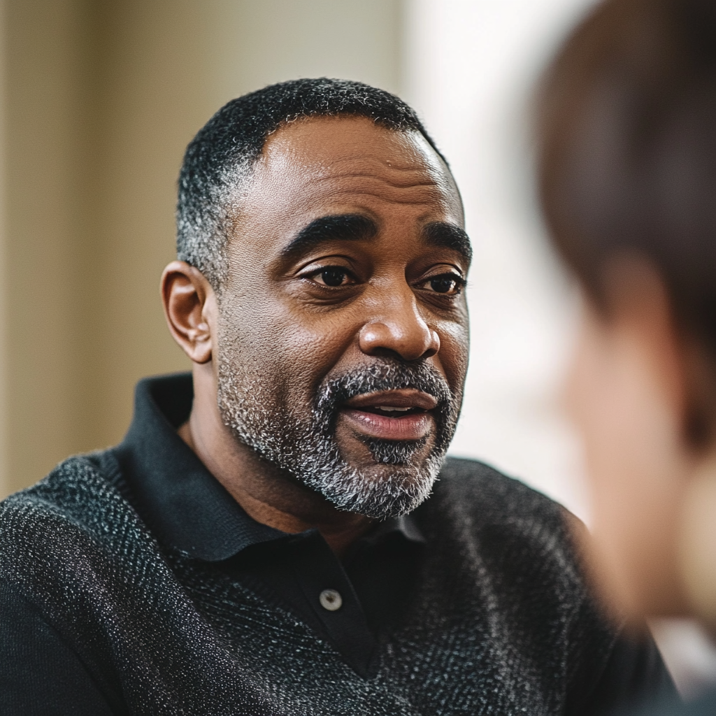 A black man talking seated in natural light.