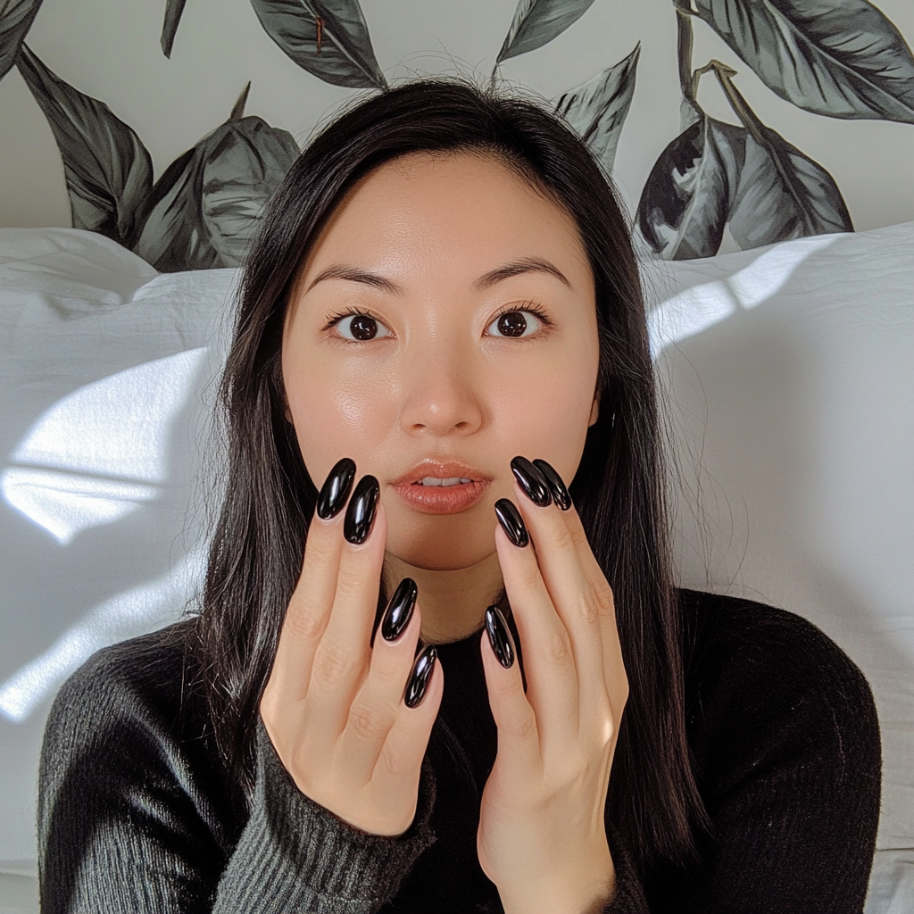 Asian woman showing nails painted black with chrome.