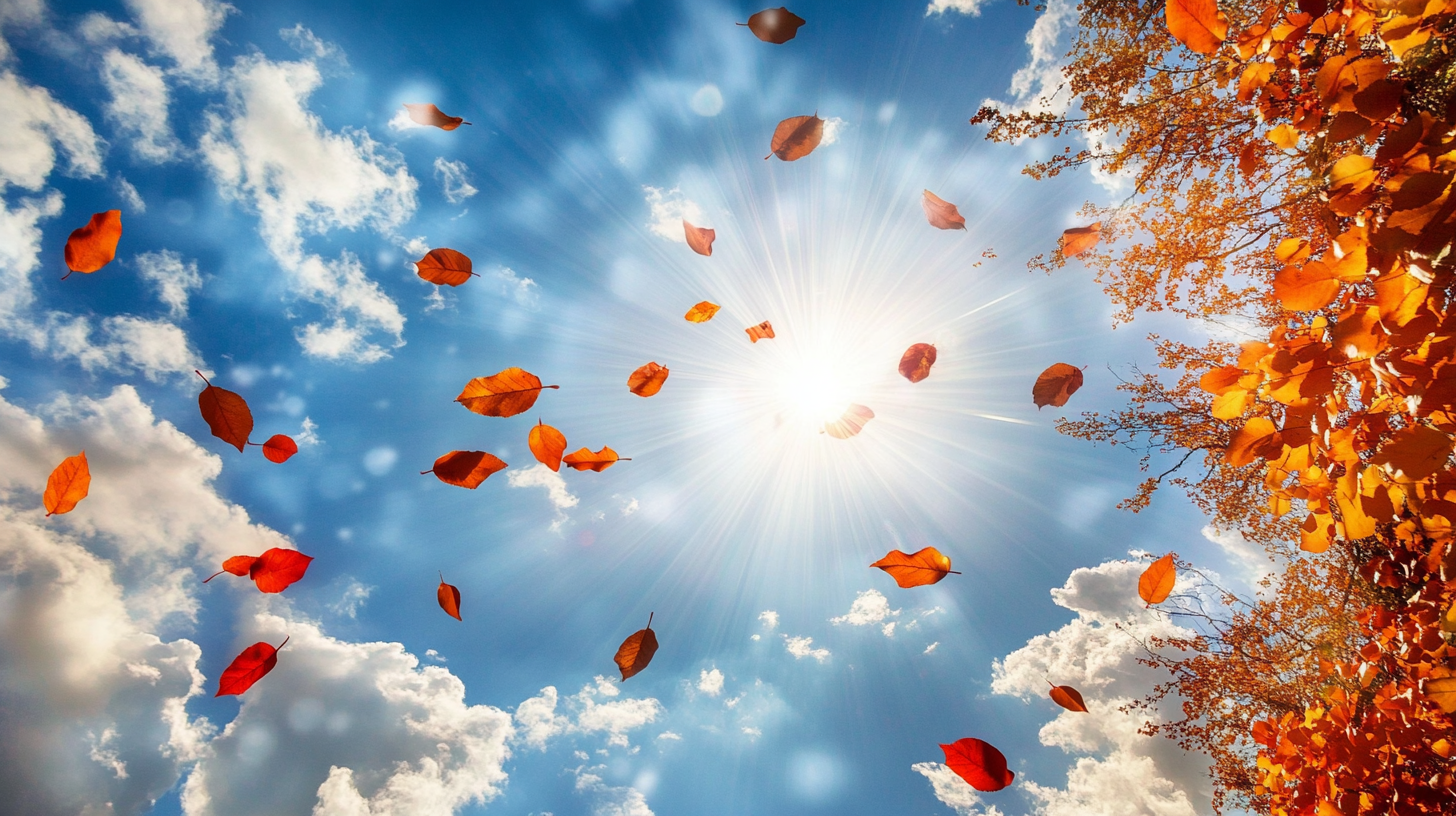 Autumn leaves swirling in blue sky with fluffy clouds.