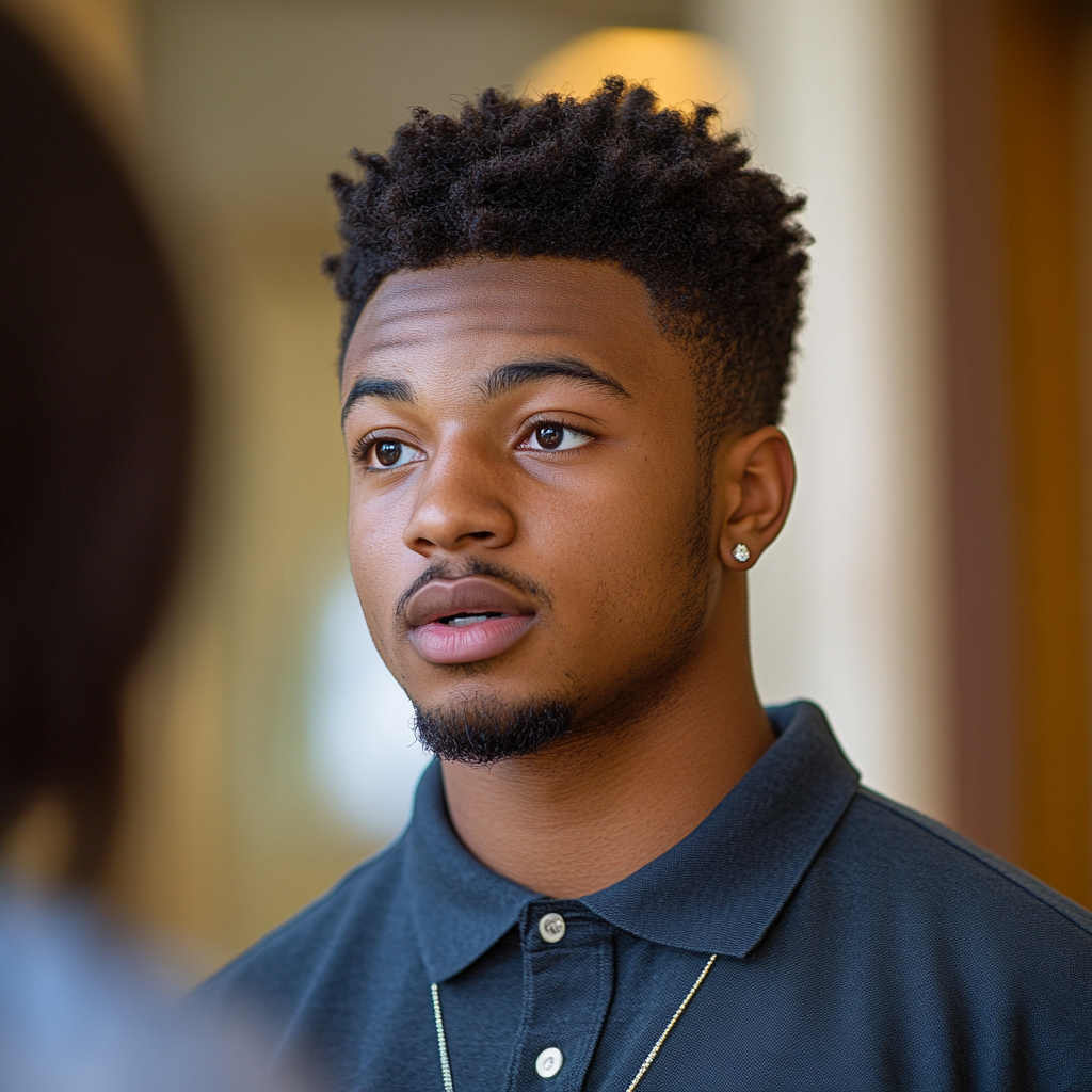 Black male freshman in polo shirt talking to professor.