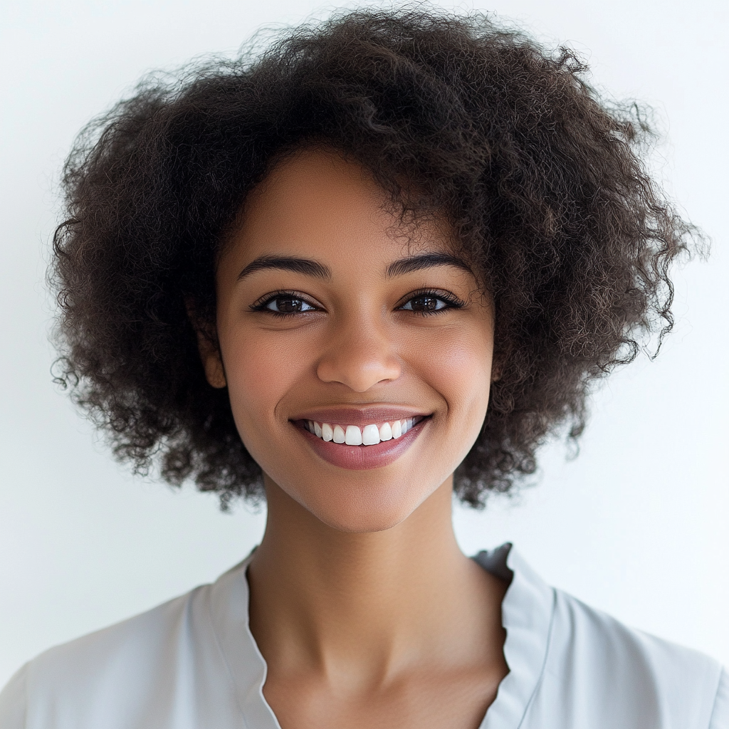 Friendly Black woman in 20s with curly hair smiling.