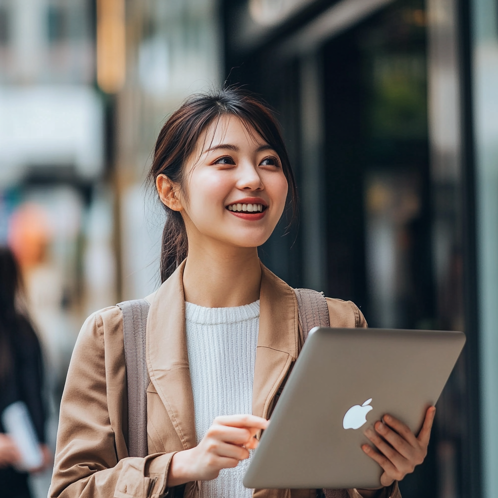 Happy Japanese woman using Mac computer, thinking positively.